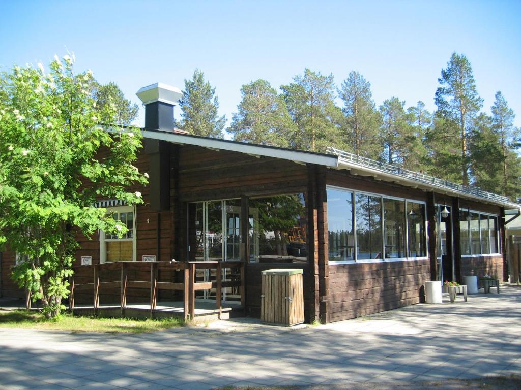 ein Holzgebäude mit einem Baum davor in der Unterkunft Camp Gielas, Arvidsjaur in Arvidsjaur