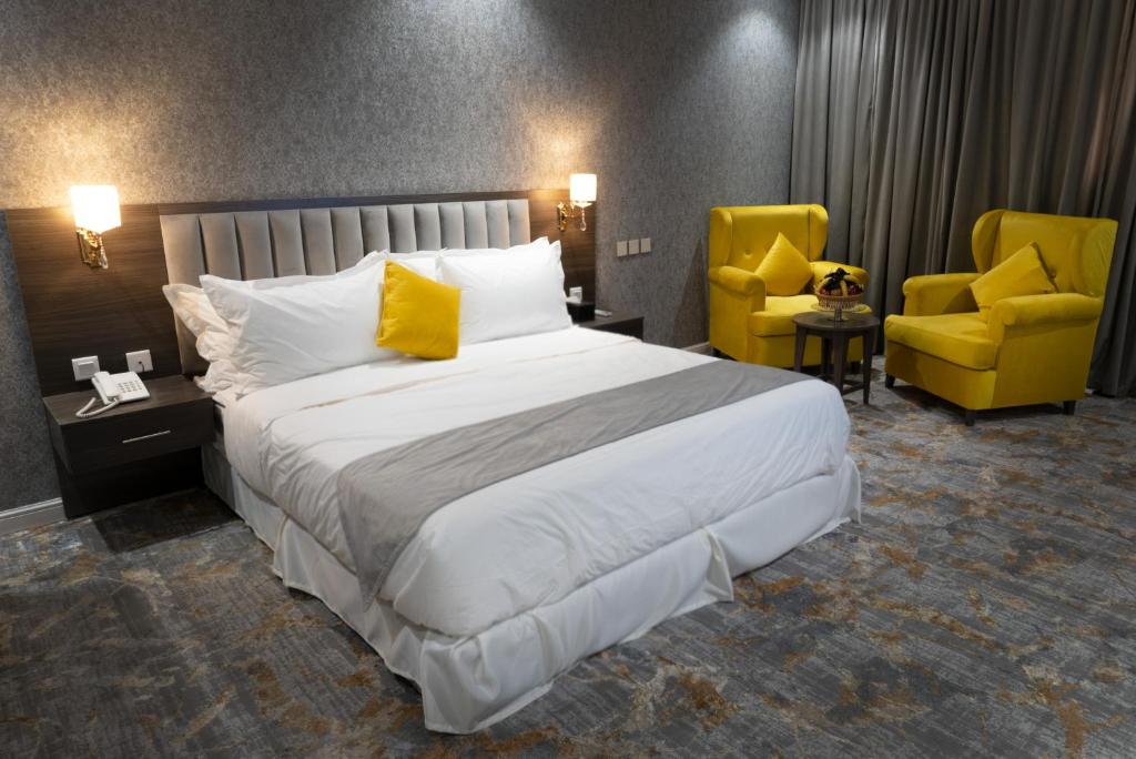 فندق دبليو اس ws في تبوك: غرفة نوم بسرير كبير وكرسيين صفراء