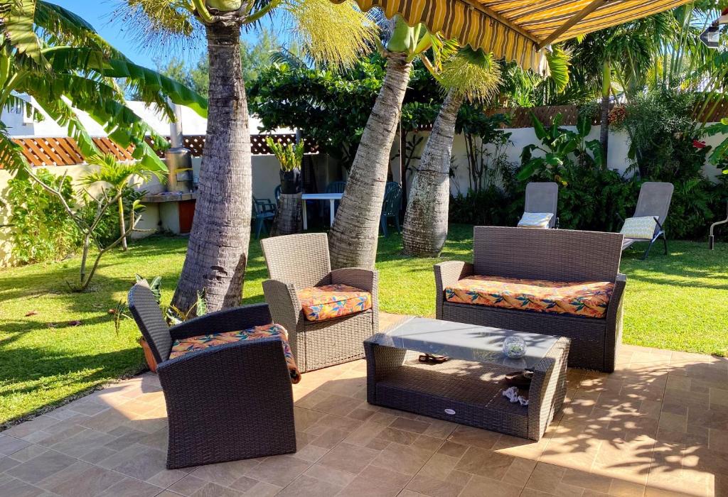 un grupo de sillas y mesas en un patio con palmeras en Chalet de 2 chambres avec jardin clos et wifi a Saint Joseph en Saint-Joseph