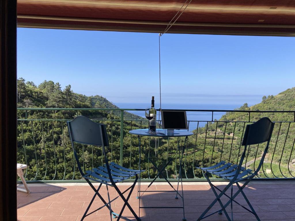 un balcón con mesa y sillas y una botella de vino en AL GEKO DEL GROPPO ☆ Breath & Relax ☆ 5 TERRE, en Volastra