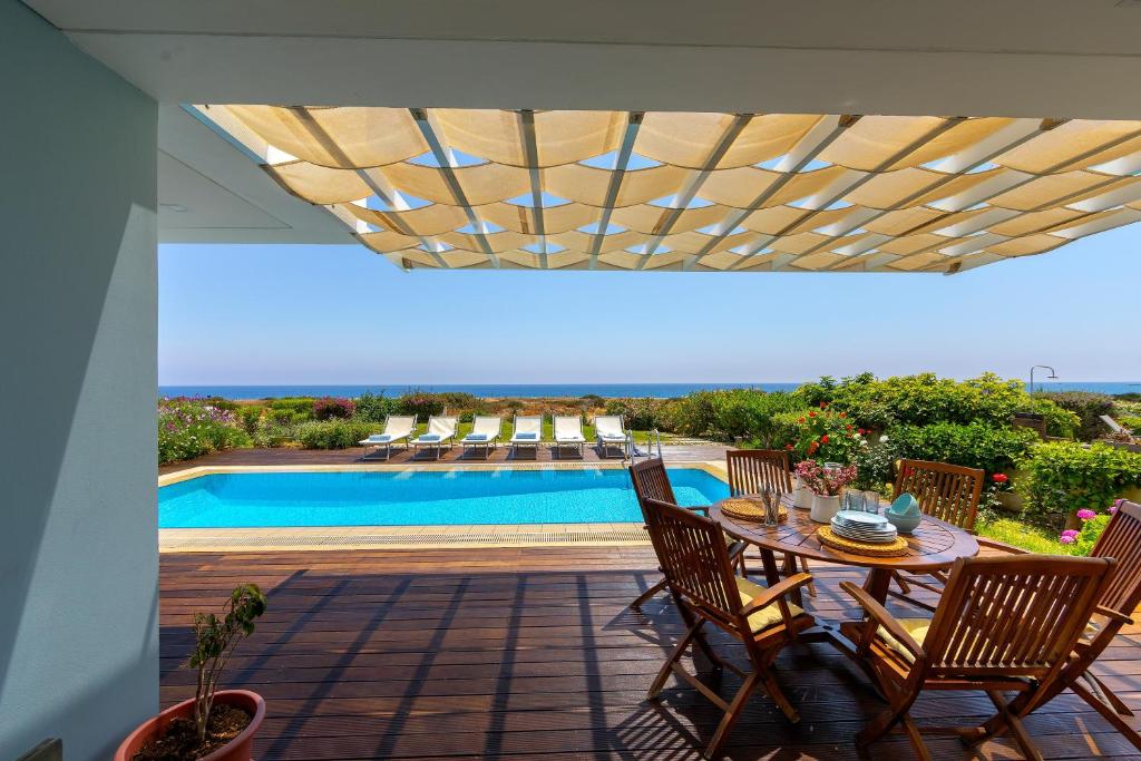 a patio with a table and chairs and a pool at Protaras Beachfront Villa Alia in Protaras