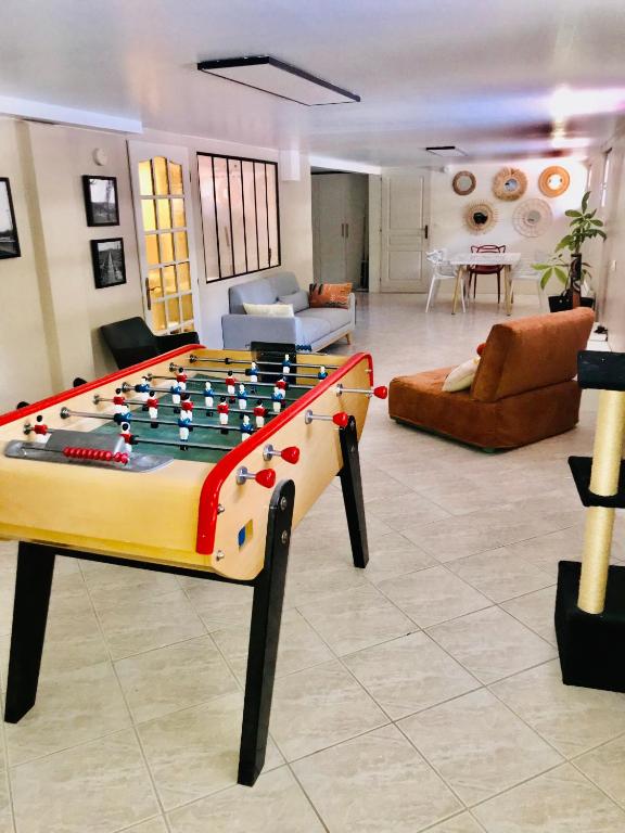 a living room with a foosball table in the middle at Appartement 120m2 dans maison avec piscine in Boissy-lʼAillerie