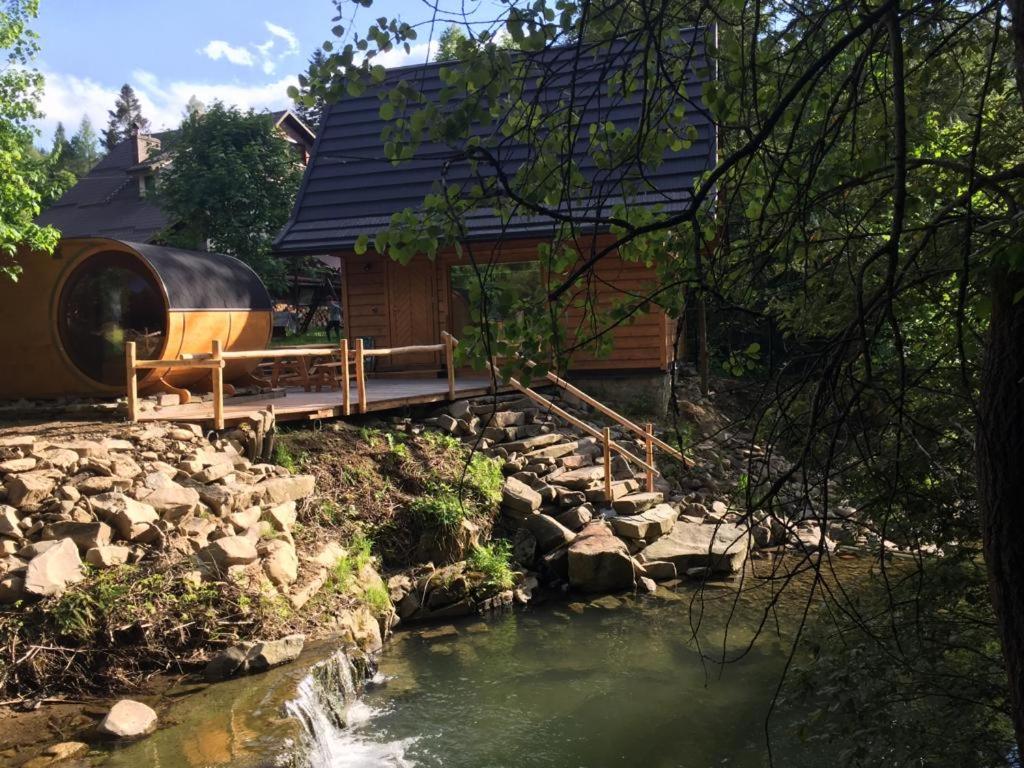 ein Blockhaus mit einer Brücke über einen Fluss in der Unterkunft Chatka z sauną nad rzeką in Żabnica