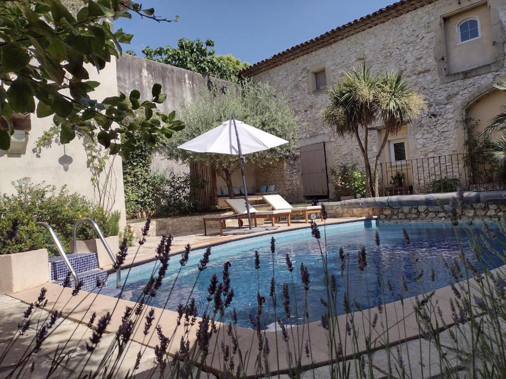 - une piscine avec une table et un parasol dans l'établissement La Maison Des Autres, piscine chauffée, chambres d'hôtes proches Uzès, Nîmes, Pont du Gard, à Saint-Géniès-de-Malgoirès