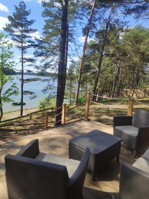 a patio with chairs and tables and a view of the water at Zakątek Wdzydze nad samym jeziorem - pierwsza linia in Borsk