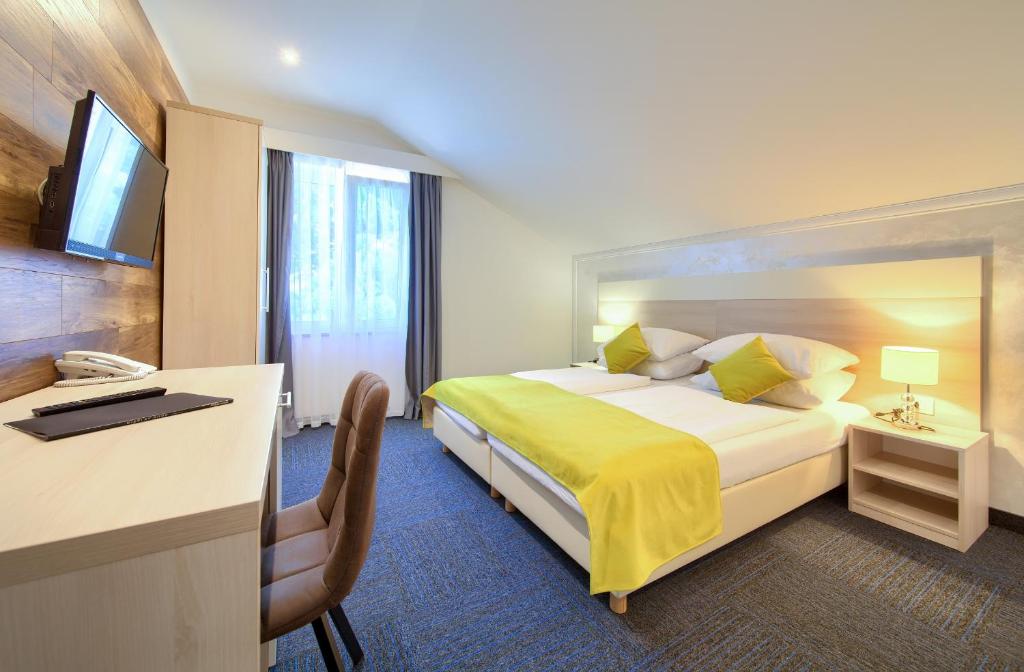 a hotel room with a large bed and a desk at Hotel Bor in Krk