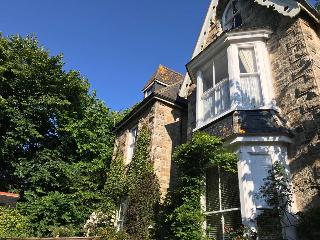 una vieja casa de piedra con hiedra. en Estoril, en Penzance