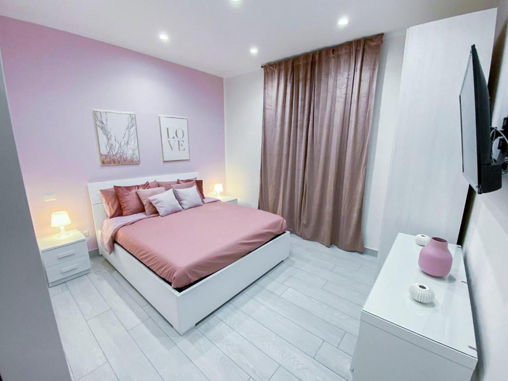 een slaapkamer met een roze bed en een televisie bij B&B VMHome in Torre del Greco