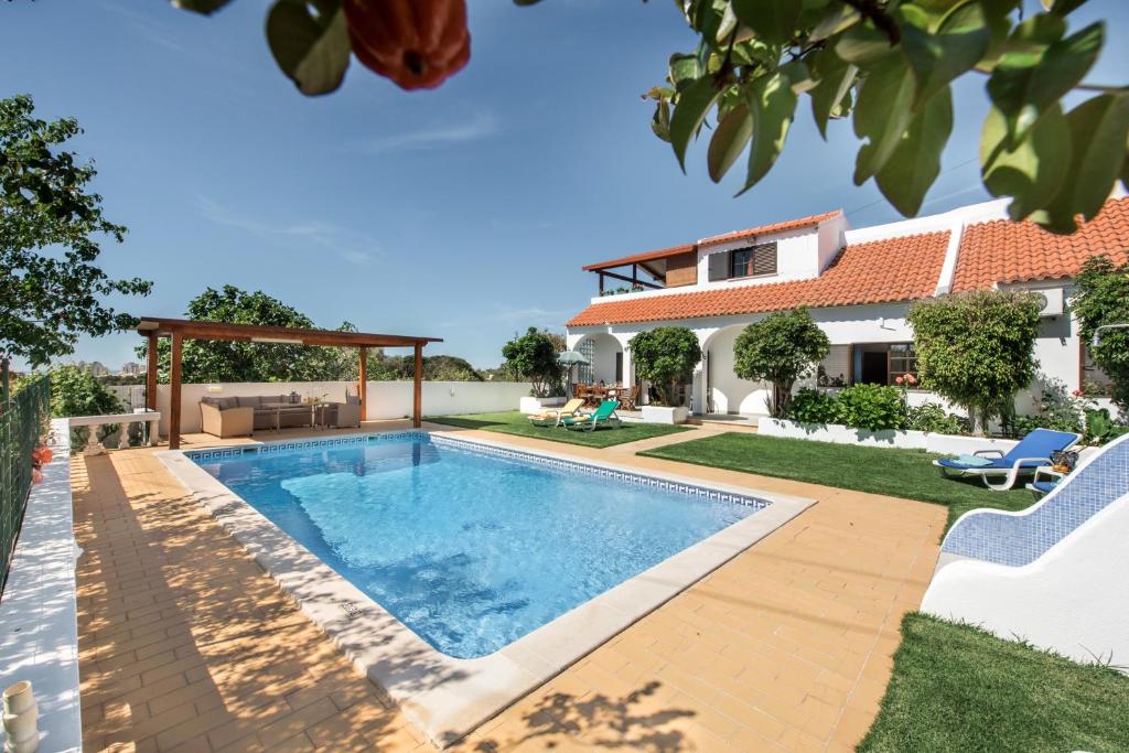a swimming pool in a backyard with a house at Villa Sao Miguel - Armacao de Pera in Armação de Pêra