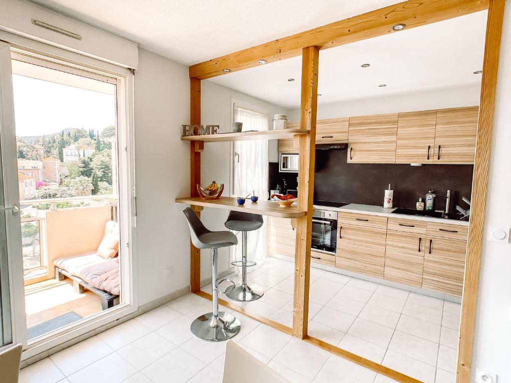 une cuisine avec un bar et une grande fenêtre dans l'établissement T2 tout confort proche centre Hyères & plages, à Hyères