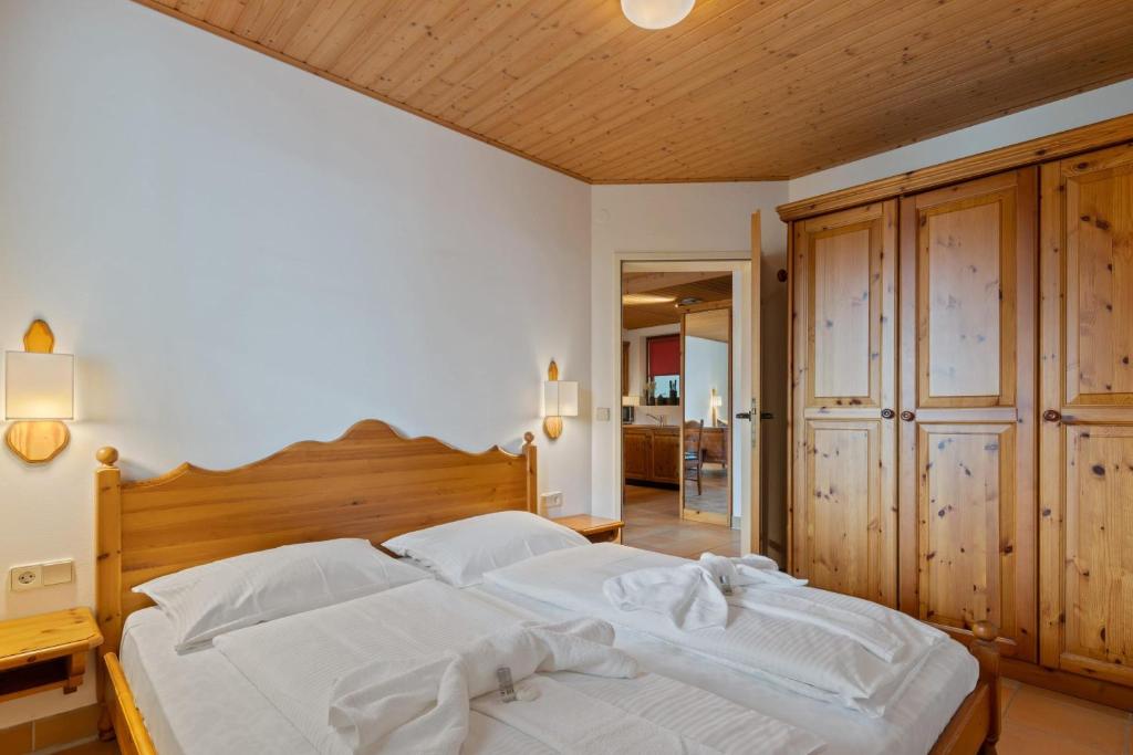 a bedroom with a large white bed with a wooden headboard at Apartment 2205 Kanzelhöhe in Treffen