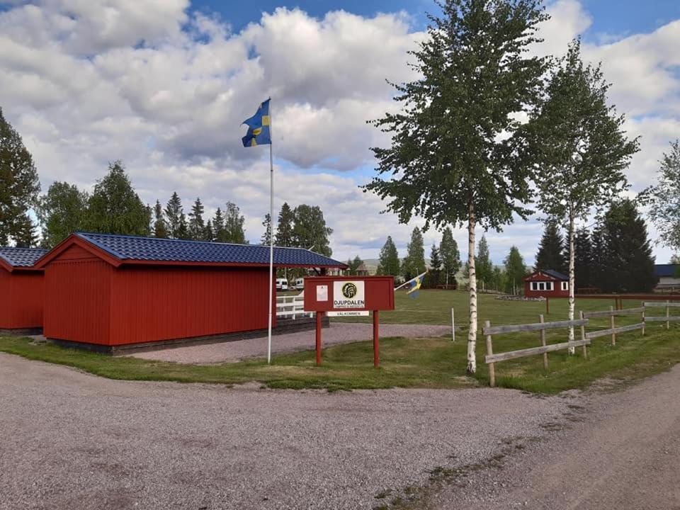 a red building with a flag next to a sign at Camping Djupdalen in Ekshärad