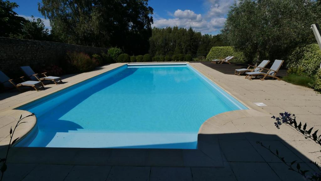 une piscine bleue avec 2 chaises longues et 2 chaises de jardin dans l'établissement Les chambres du Manoir de Kerhel, à Locoal-Mendon