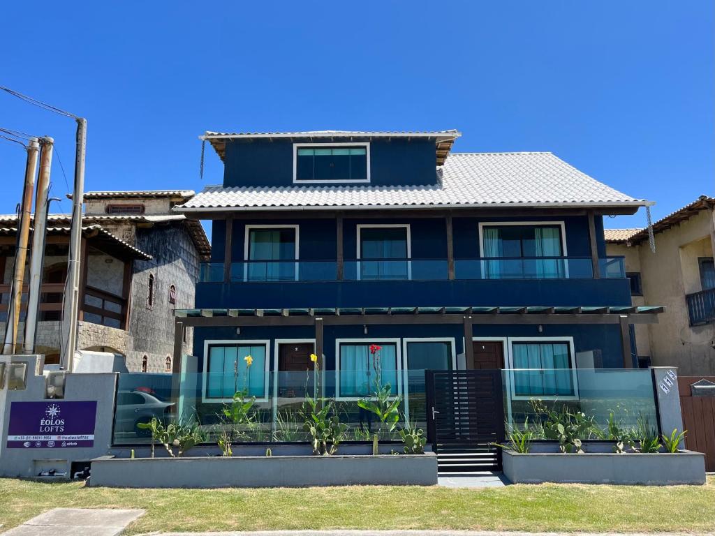 uma casa azul com plantas em frente em Éolos Loft's - Cabo Frio em Cabo Frio