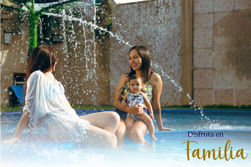 zwei Frauen und ein Kind sitzen in einem Brunnen in der Unterkunft Hotel La Cascada - Lago Agrio in Nueva Loja