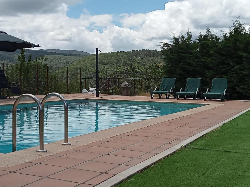 ein Schwimmbecken mit drei Stühlen daneben in der Unterkunft CASA RURAL VERSOS in San Martín del Castañar