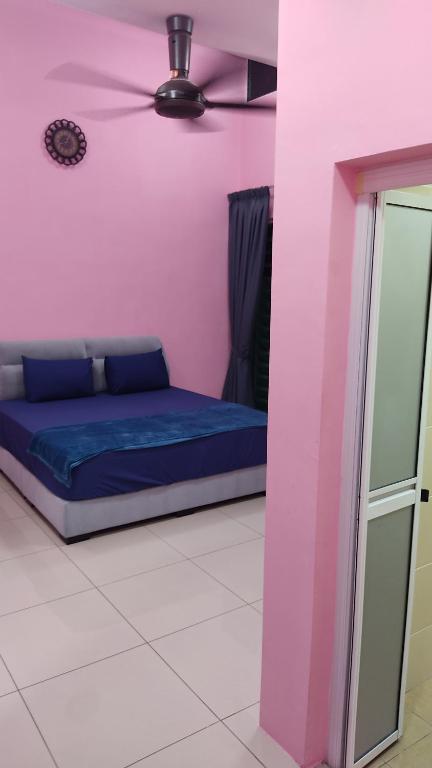 a bed in a pink room with a ceiling fan at PRESTIJ H0MESTAY in Balik Pulau