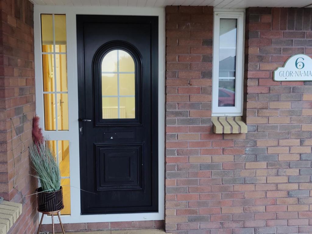 una puerta negra en una casa de ladrillo con una ventana en 6 Connorville en Luddan