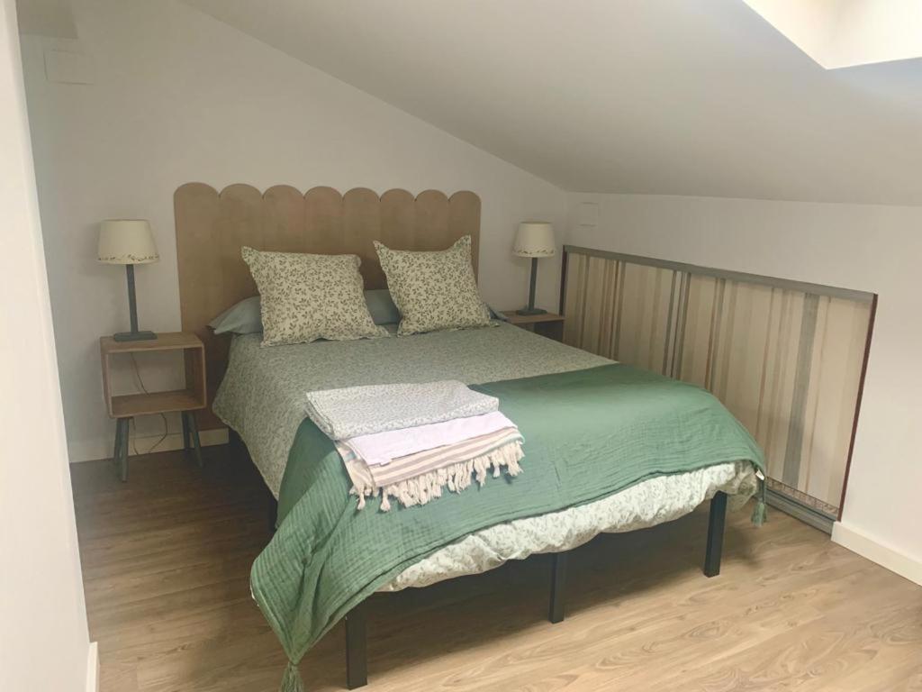 a bedroom with a large bed with a green blanket at Precioso apartamento castro Urdiales in Castro-Urdiales