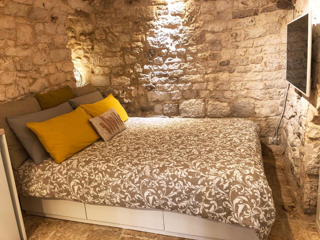 Bett in einem Zimmer mit einer Steinmauer in der Unterkunft Tao Stones - Alloggio in pietra in Conversano