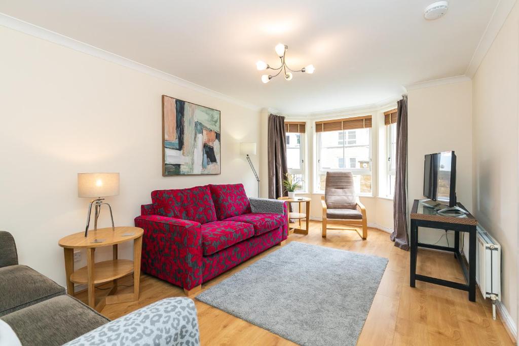 a living room with a red couch and a tv at Dicksonfield Quiet Central Family Apartment with Parking in Edinburgh