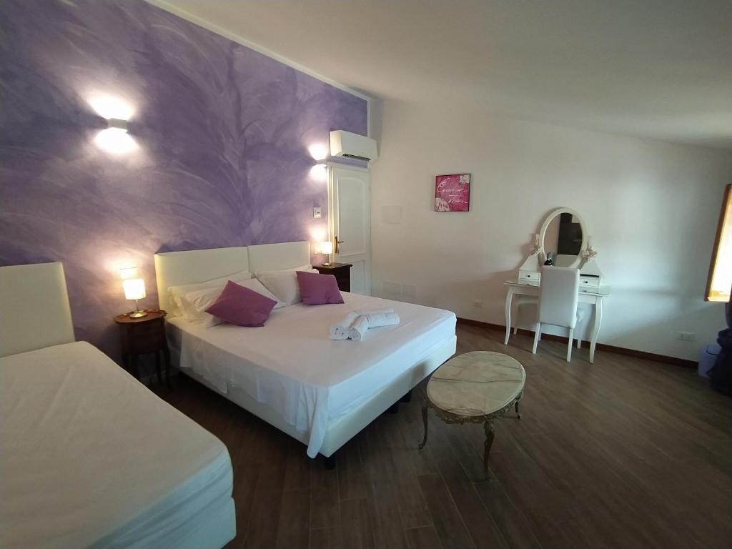 - une chambre avec un grand lit blanc et une table dans l'établissement B&B Villa la Bouganville, à Camaiore
