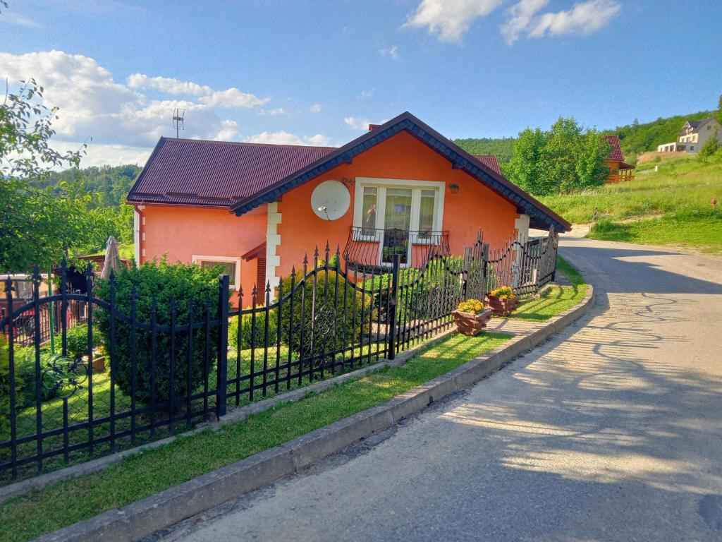 mały pomarańczowy dom z czarnym płotem w obiekcie Agroturystyka u Janosika w mieście Bozkow