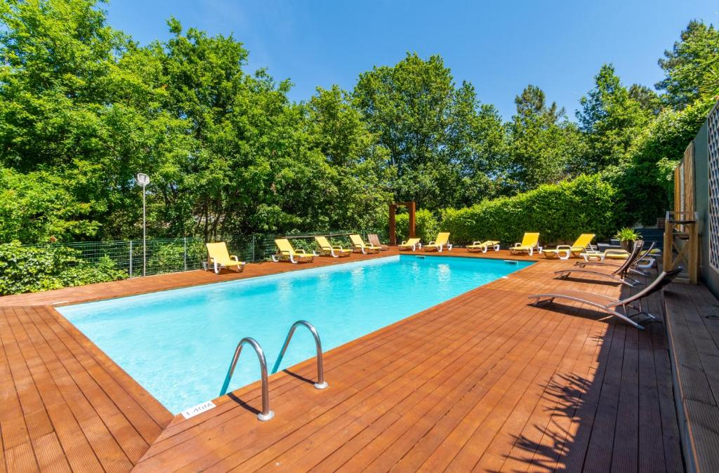 una piscina con sedie a sdraio su una terrazza in legno di Apartamentos Do Ermal a Vila Boa