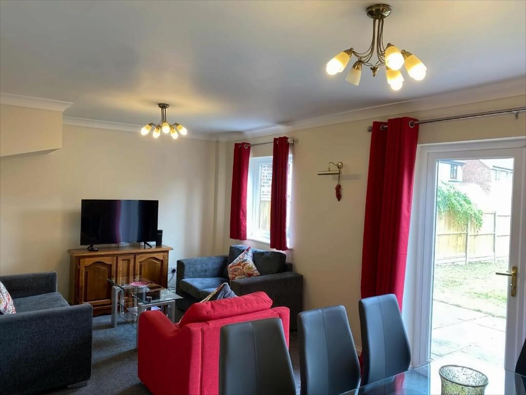 a living room with red curtains and a tv at Exclusive, Homely & Warm Cambridge 4 bed house with free parking, garden and sleeps 10 in Cambridge