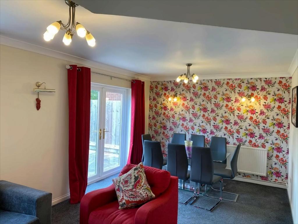 a dining room with a red chair and a dining table at Exclusive Homely Cambridge 4 bed house with free parking, big garden and sleeps 10 in Cambridge