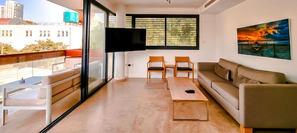 uma sala de estar com um sofá e uma televisão em BnBIsrael apartments - Kalisher Ophrys em Tel Aviv