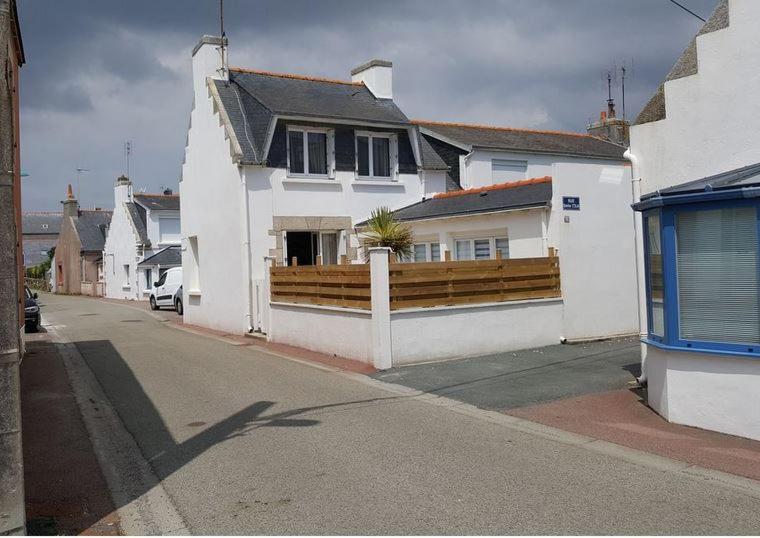 szereg białych domów z drewnianym płotem w obiekcie Maison de vacances 3* à 50m de la plage w mieście Tréffiagat