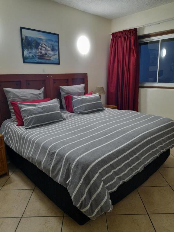 a large bed in a bedroom with a red curtain at Stella Maris 194 Amazimtoti Self Catering accommodation in Amanzimtoti