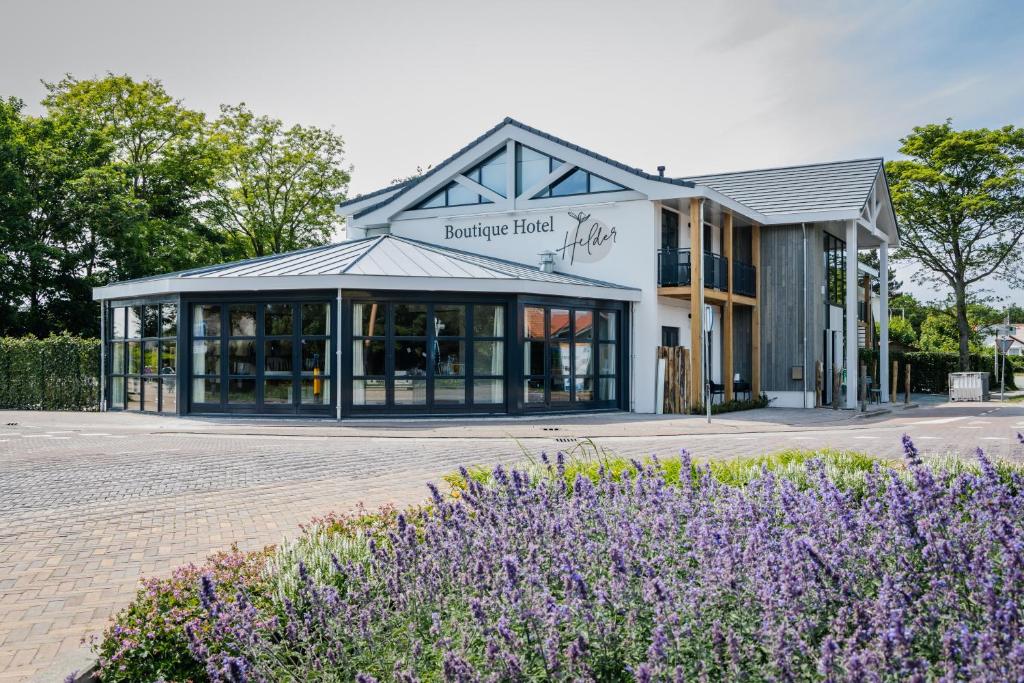 a building with purple flowers in front of it at Boutique Hotel Helder I Kloeg Collection in Renesse