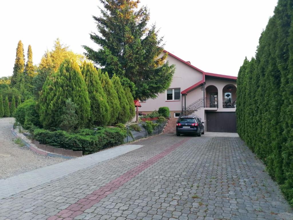 a house with a car parked in front of a driveway at Pokoje Gościnne Sandomingo in Sandomierz