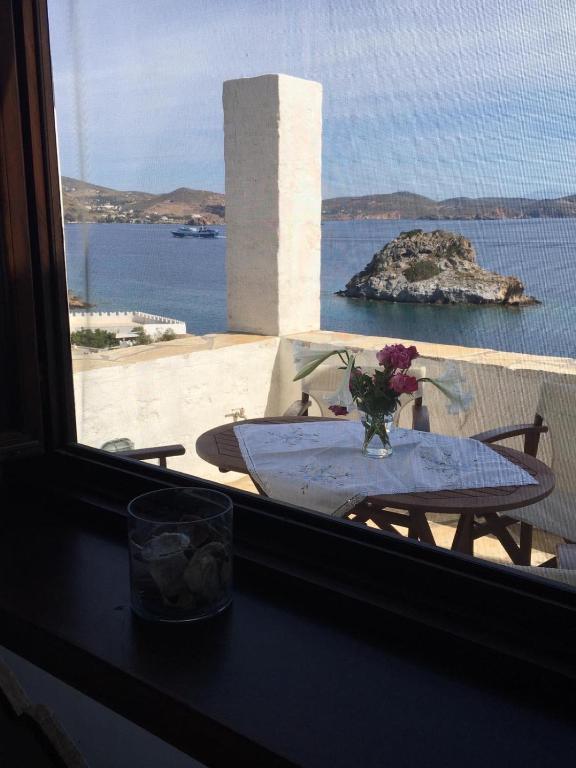 a table with a vase of flowers on a window at Loukakia apartments in Patmos