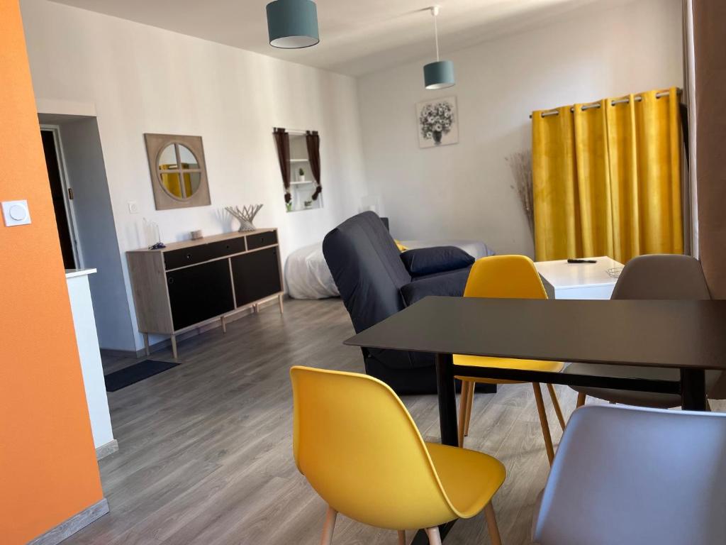 sala de estar con mesa y sillas amarillas en Millau Superbe Studio 35m2 Centre ville calme et Ajouré, en Millau