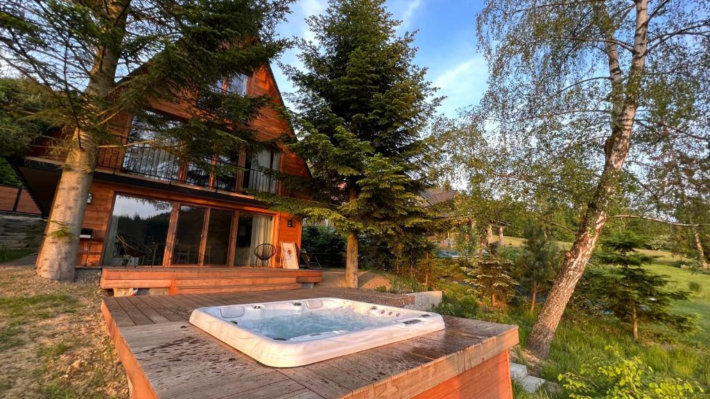 uma banheira de hidromassagem num deque em frente a uma casa em Mountain Cottage Gorcówka em Poręba Wielka