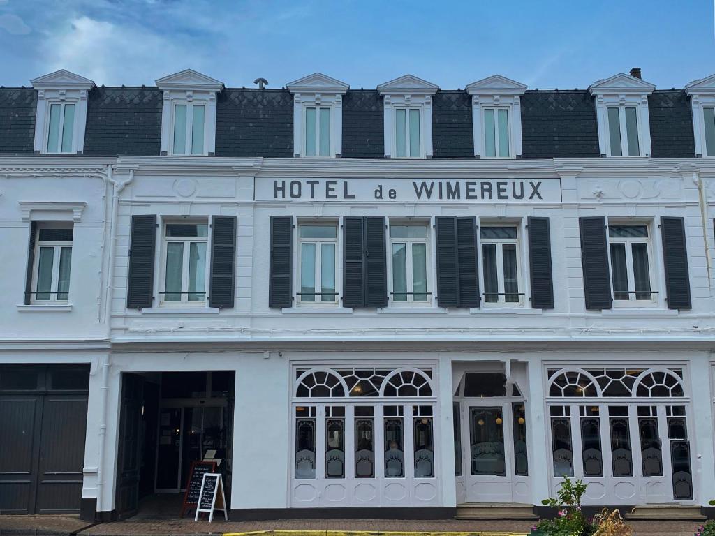 - un grand bâtiment blanc avec un panneau dans l'établissement Hôtel De Wimereux, à Wimereux