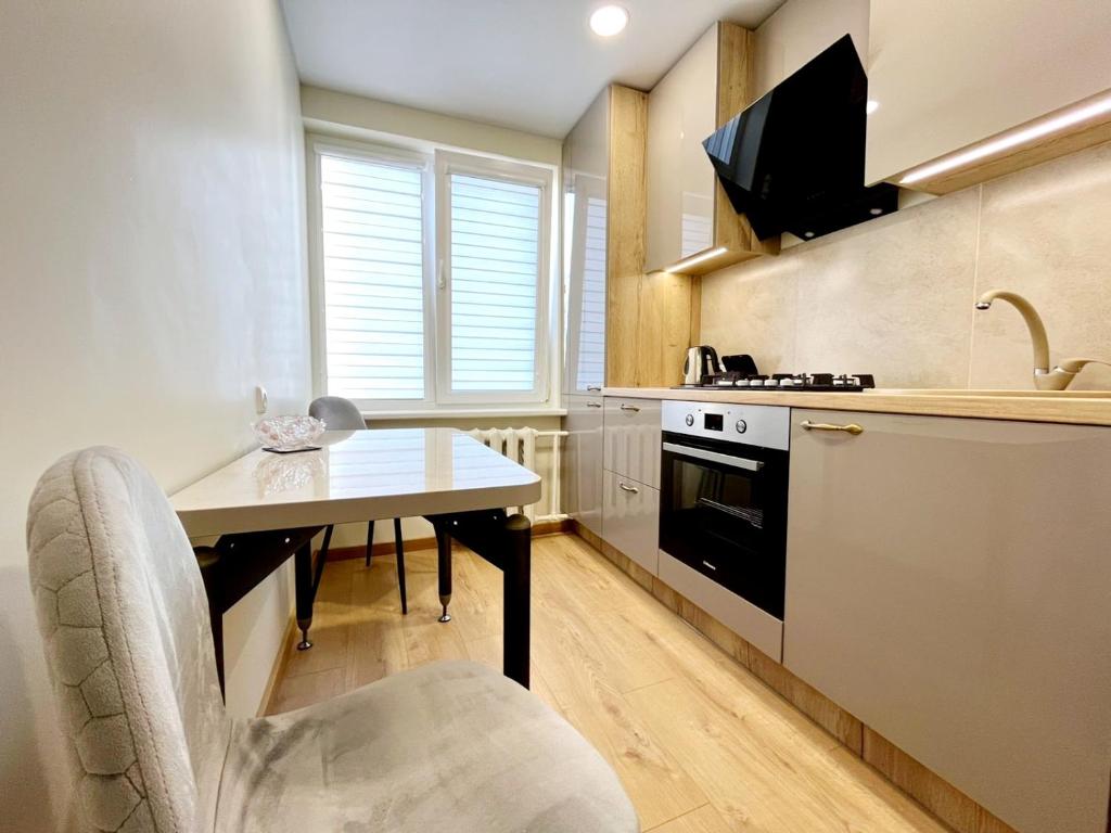 a kitchen with a table and a chair and a sink at M&M Apartment V SELF CHECK-IN in Panevėžys