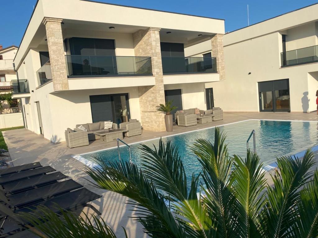 a villa with a swimming pool in front of a building at Vila Softic Azra in Umag
