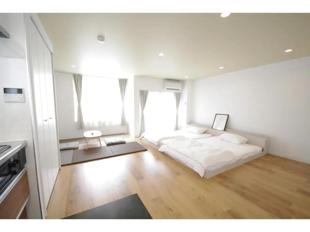 a white bedroom with a bed and two windows at HOTEL APT SESELA - Vacation STAY 12883 in Kanazawa