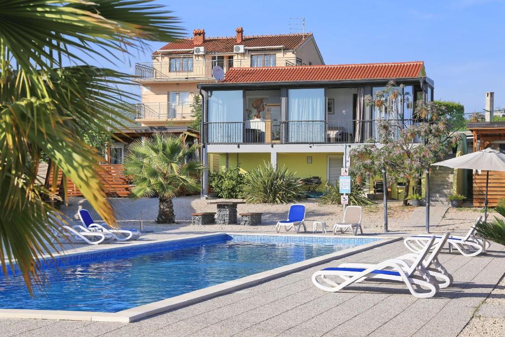 uma piscina com duas cadeiras e uma casa em Apartman "TURANJ" em Turanj