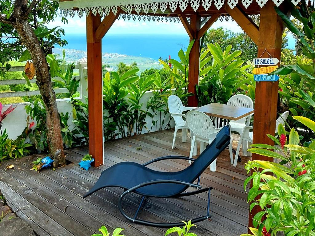 a wooden deck with a table and chairs on it at Bélavue & SPA Privé, avec vue panoramique sur mer, jardin créole paysager, jacuzzi privé in Bouillante