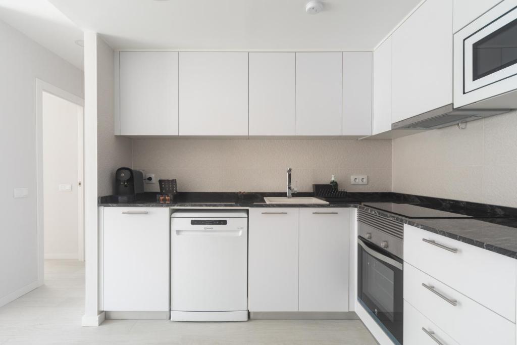 a white kitchen with white cabinets and appliances at Reinapart Valencia Beach in Valencia