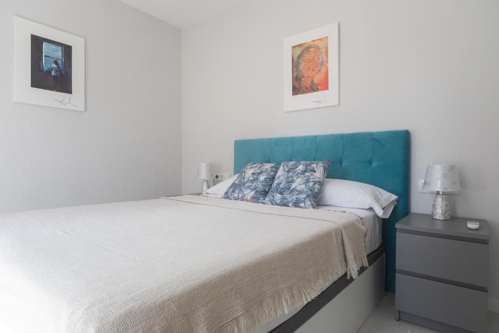 a bedroom with a large bed with a blue headboard at Reinapart Valencia Beach in Valencia