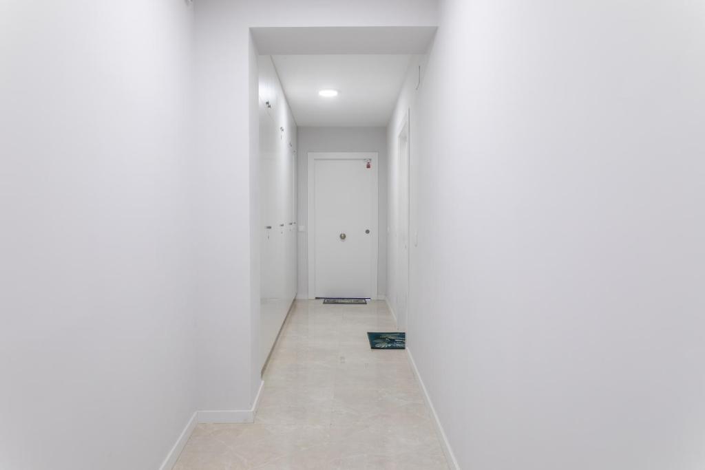 an empty hallway with white walls and a door at Reinapart Valencia Beach in Valencia