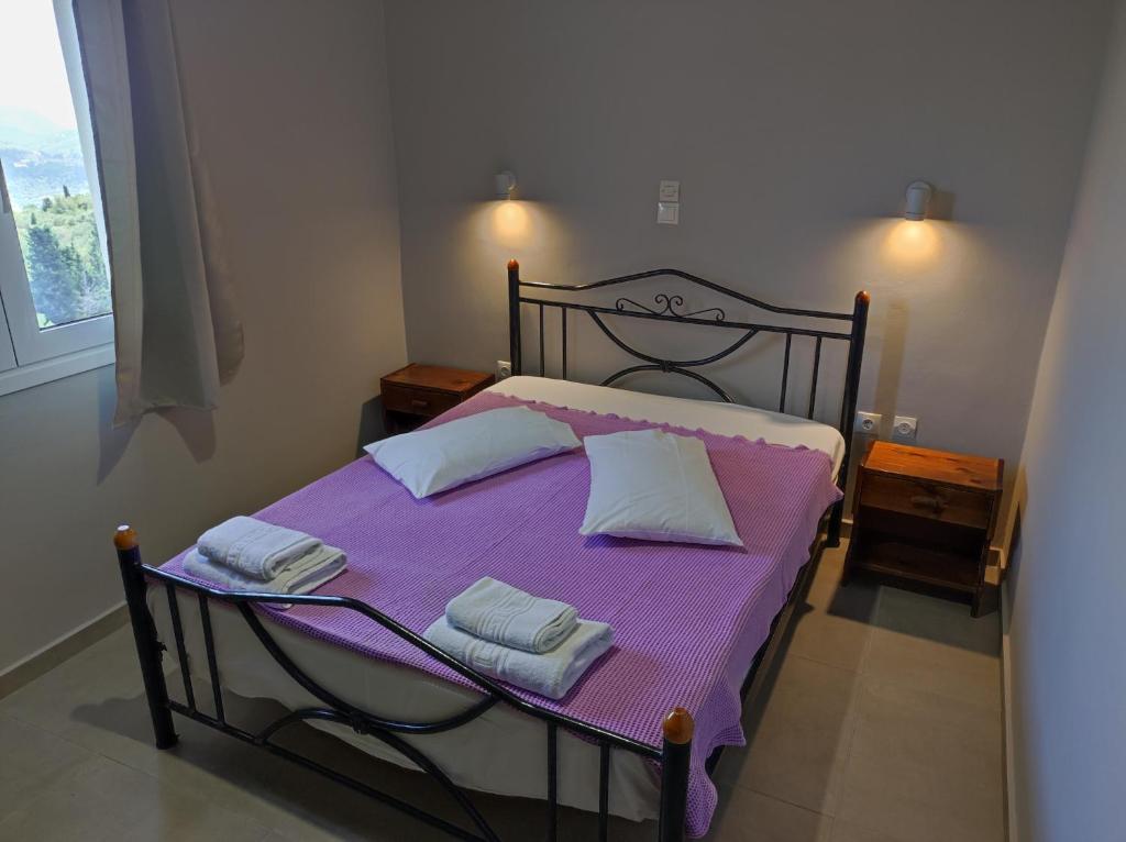 1 dormitorio con 1 cama con sábanas y toallas púrpuras en San Pedro, en Vasiliki