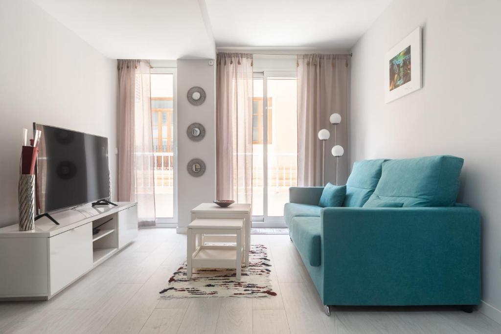 un salon avec un canapé bleu et une télévision dans l'établissement Reinapart Valencia Beach, à Valence