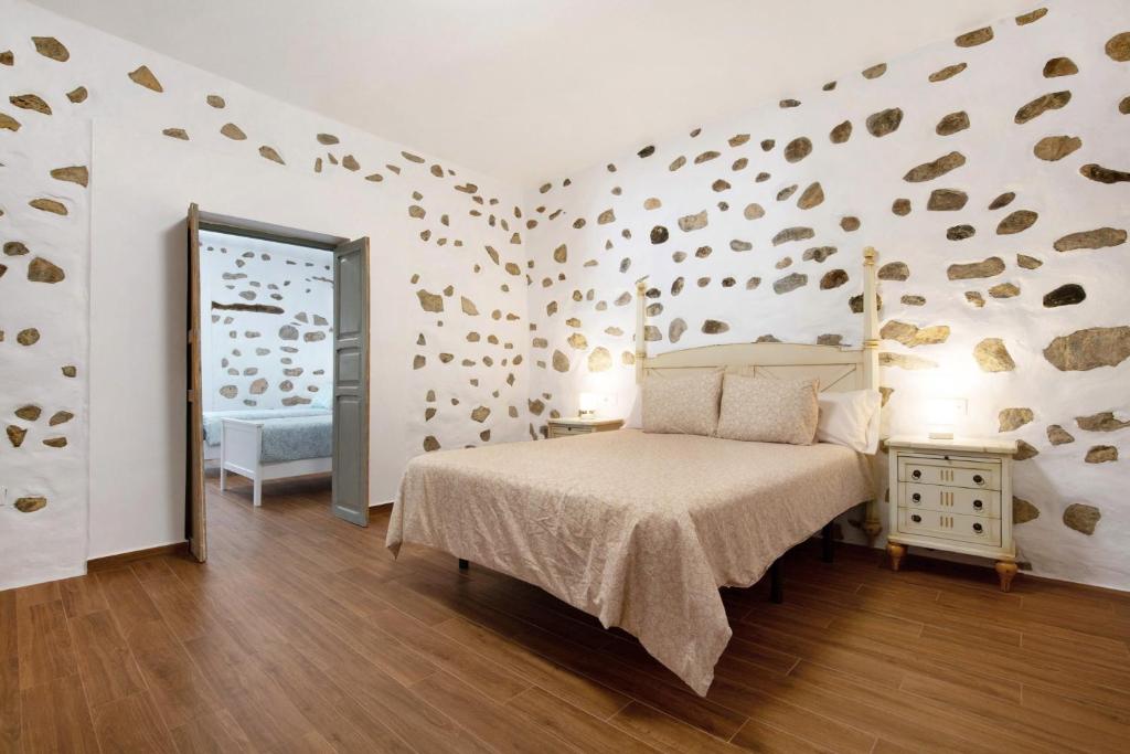 1 dormitorio con 1 cama y una pared cubierta de monedas en Casa Milagrito Betancuria en Betancuría